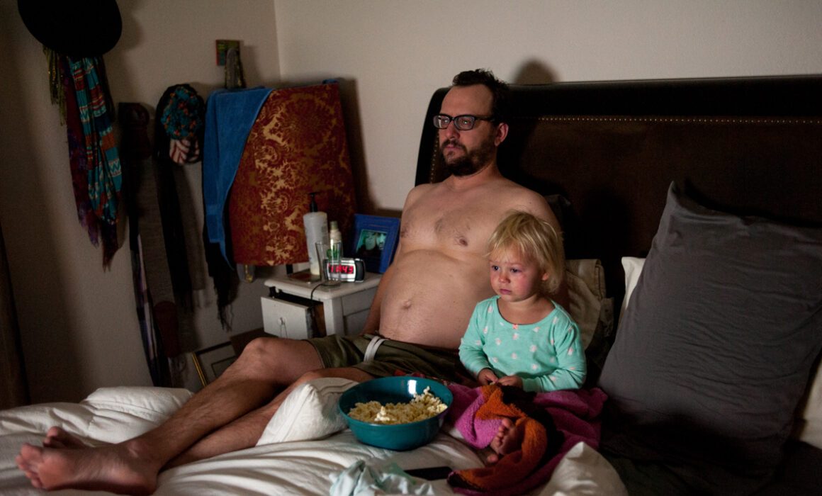 Dad watching TV with toddler daughter